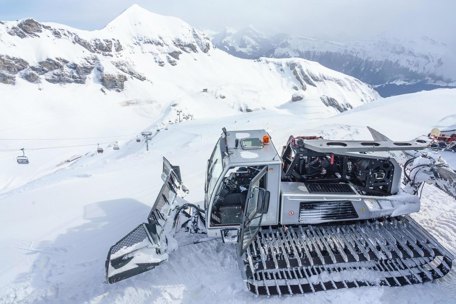 macchina per la cura della neve sulla collina di neve nelle alpi svizzere foto