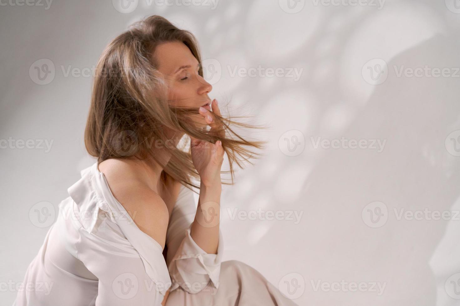 riflessivo giovane donna seduta su pavimento con sua testa nel leggero leggero Abiti isolato su bianca sfondo con leggero foto
