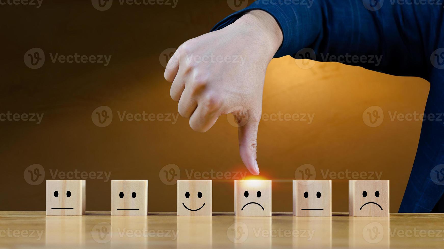 cliente servizio valutazione e soddisfazione sondaggio servizio valutazione concetti.uomo d'affari mano pollici giù scegliere il di legno bloccare con il infelice viso Sorridi viso icona su di legno cubo. foto