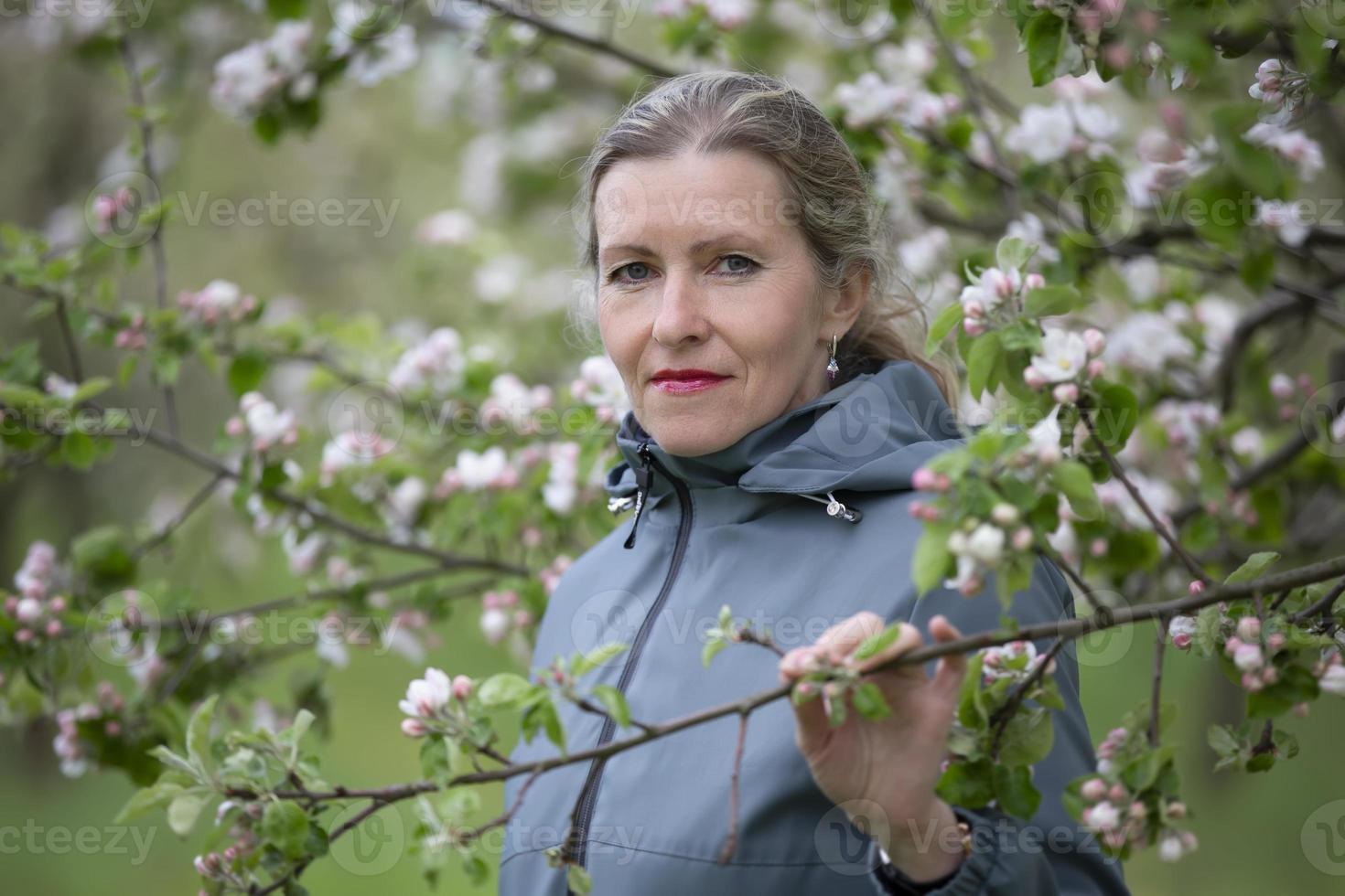 un anziano donna nel un' fioritura giardino sembra a il telecamera. foto