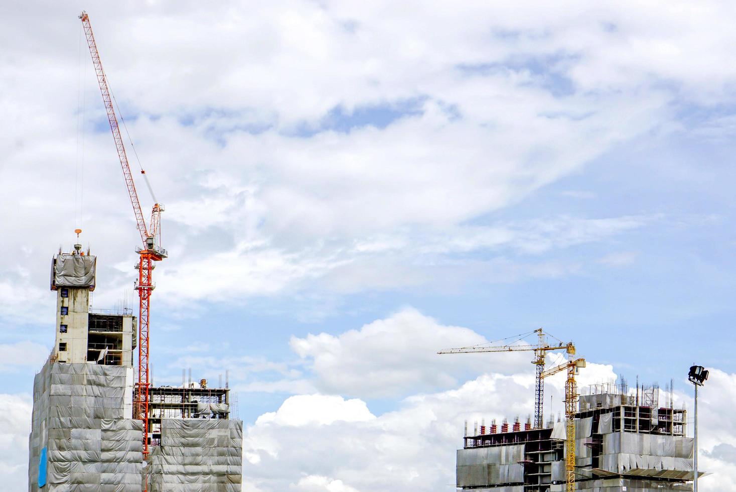 sollevamento gru Lavorando edificio costruzione su luminosa blu cielo e grande nube sfondo. foto