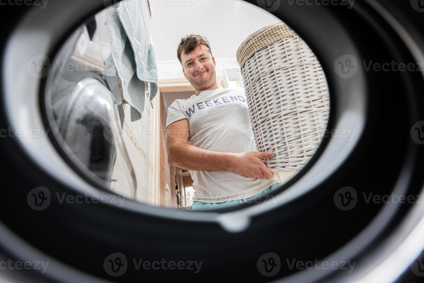 uomo con cestino, Visualizza a partire dal lavaggio macchina dentro. maschio fa lavanderia quotidiano routine. foto