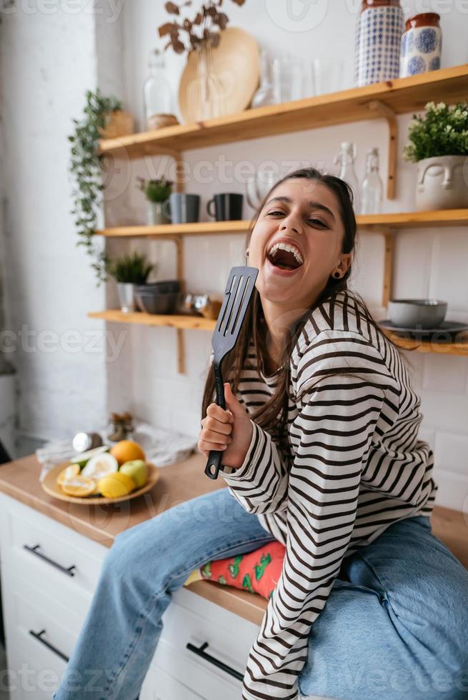 divertente donna cantando in spatola, Tenere spatola come microfono. foto