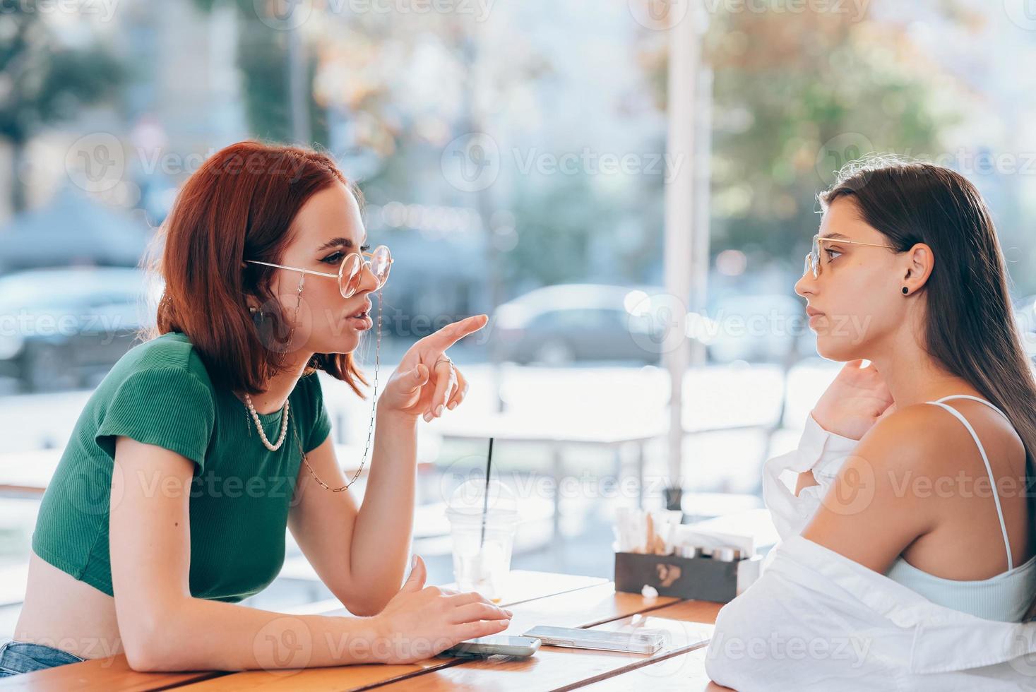 Due bella amiche parlando mentre seduta nel un' bar all'aperto foto