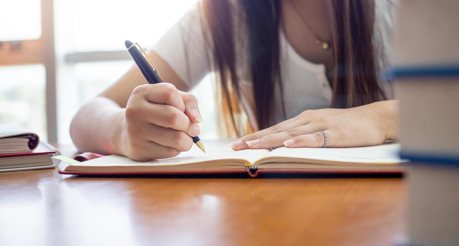 femmina studenti scrittura e lettura nel il biblioteca foto