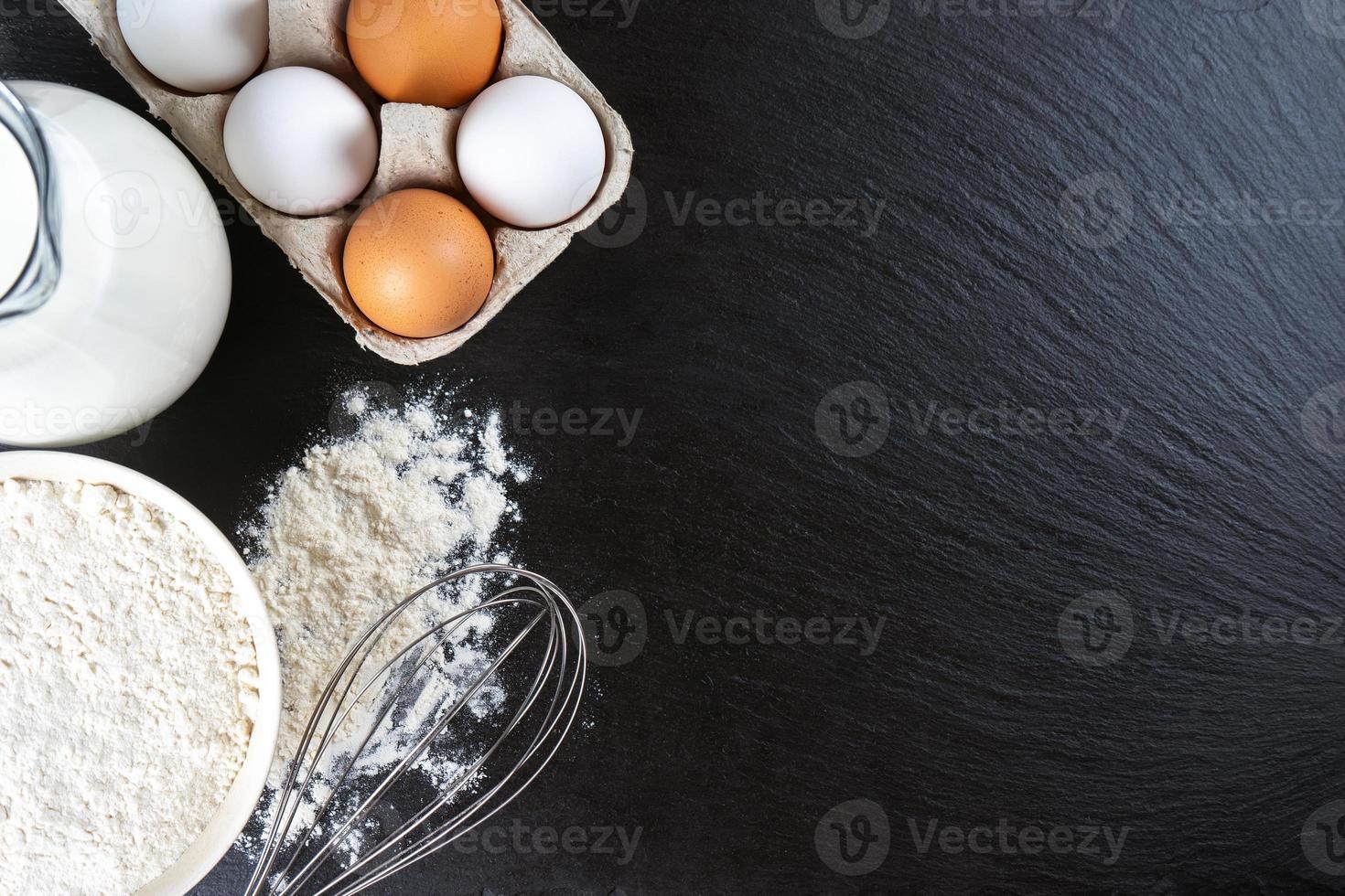 cottura al forno ingredienti Farina, uova, latte, bakeware su nero ardesia sfondo con copia spazio foto