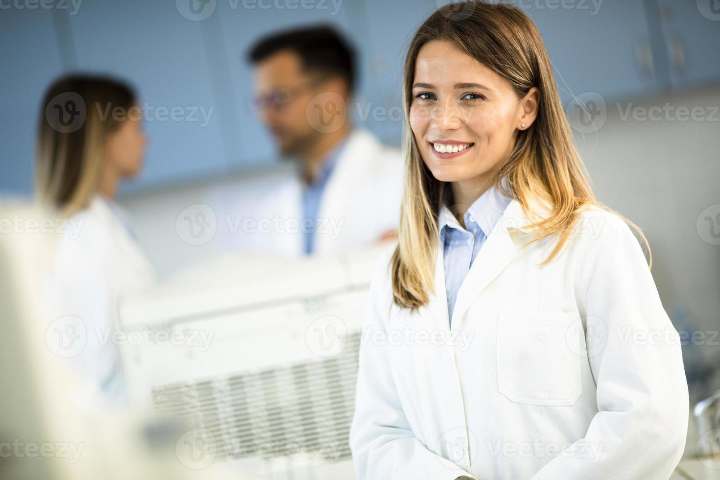 scienziato femminile in camice bianco in piedi nel laboratorio biomedico foto