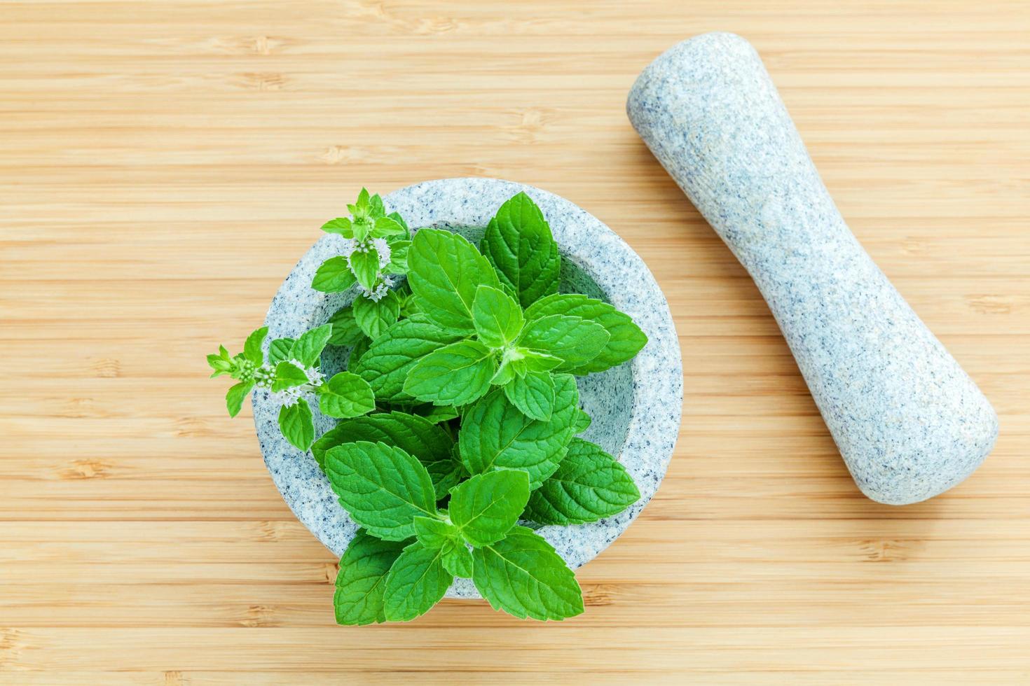 foglie di menta piperita fresca in un mortaio su un tagliere di bambù foto