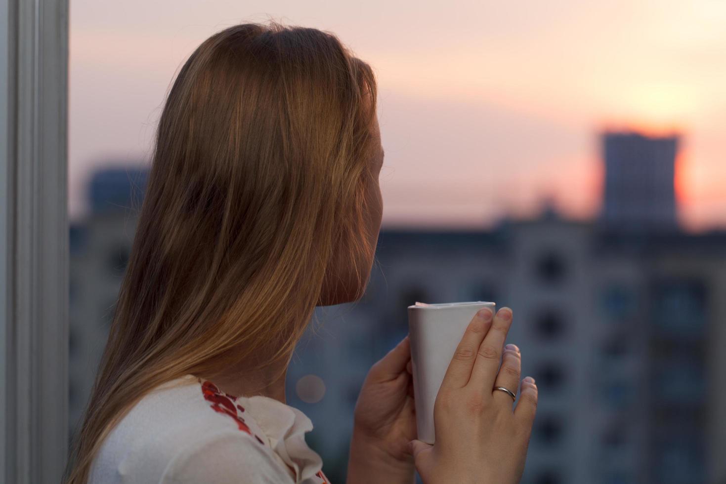 donna che beve il tè guardando un tramonto foto