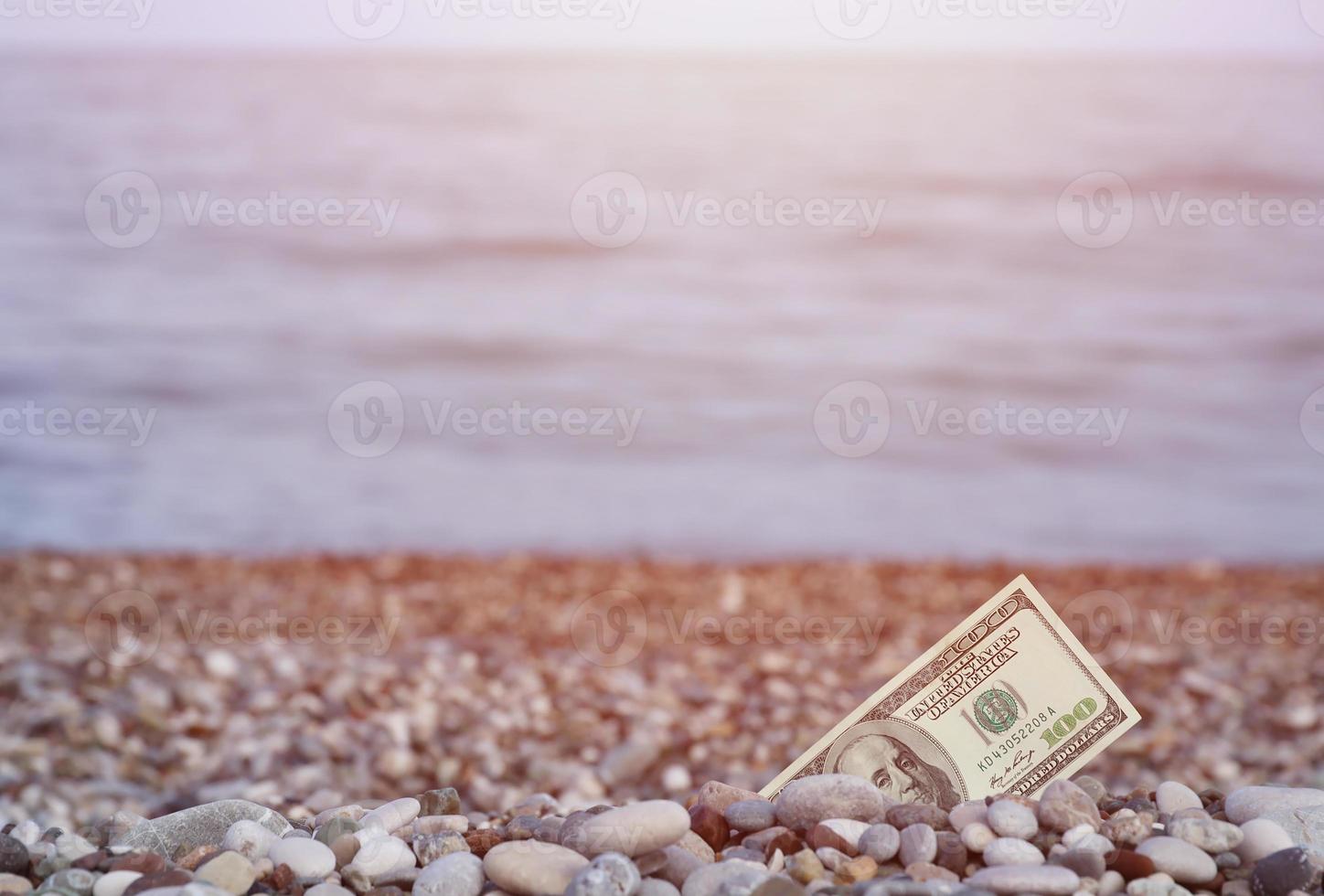 centinaio dollari metà coperto con il giro rocce menzogna su spiaggia foto