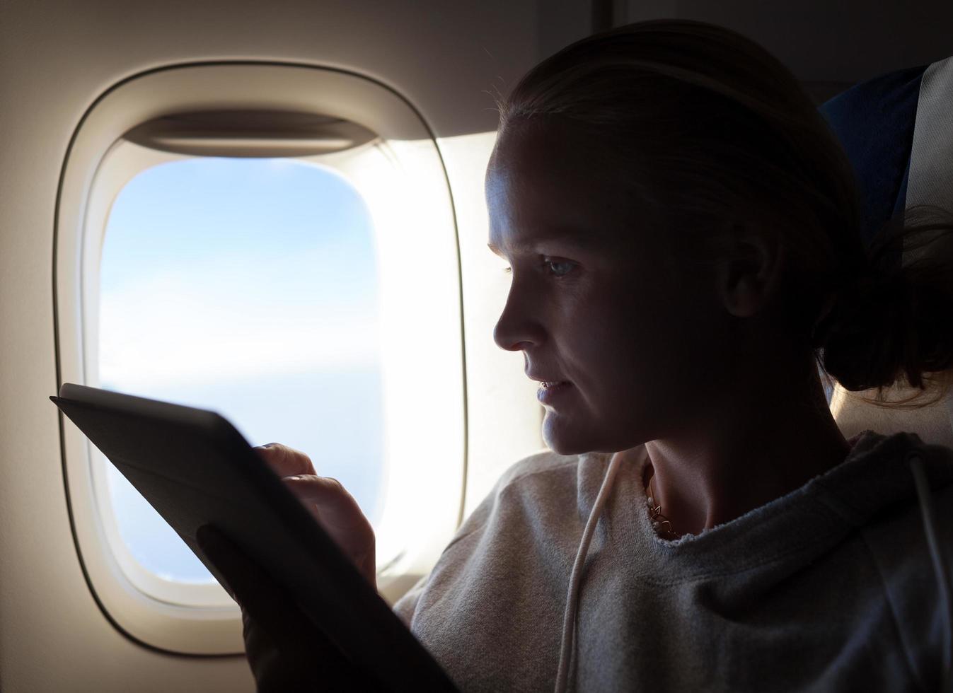 donna con una tavoletta in un aeroplano foto