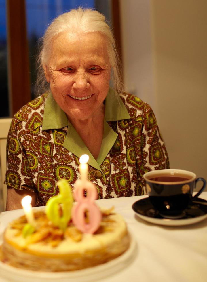 nonna che spegne le candeline sulla torta del compleanno foto