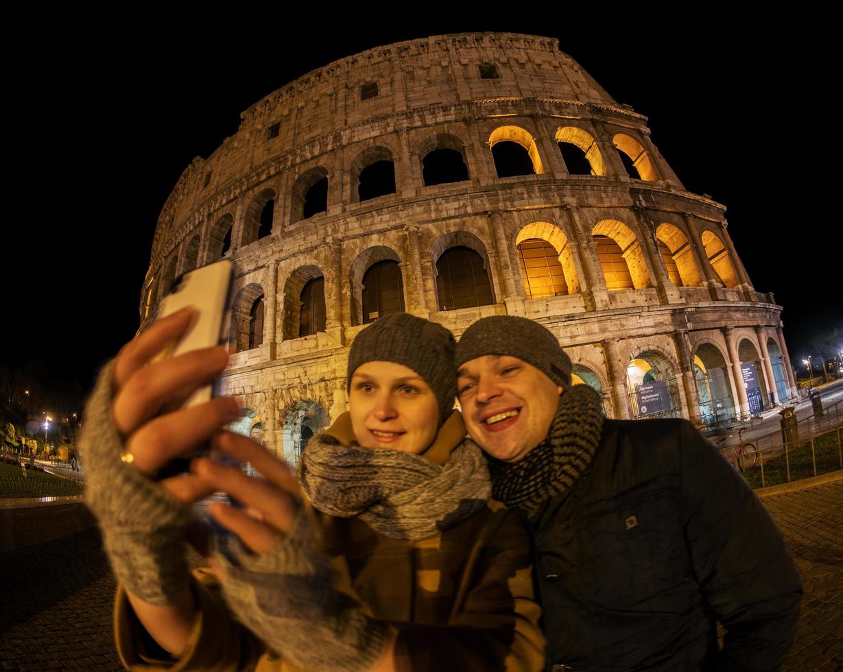 coppia felice prendendo un selfie davanti al Colosseo foto