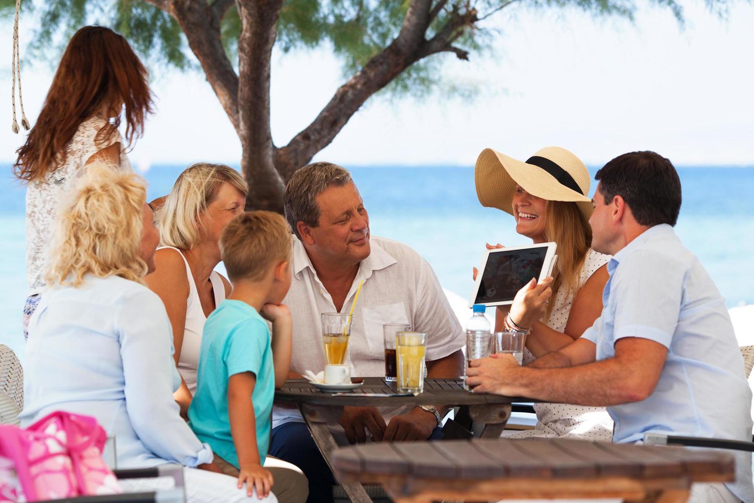 famiglia guardando la foto su una tavoletta in un caffè all'aperto