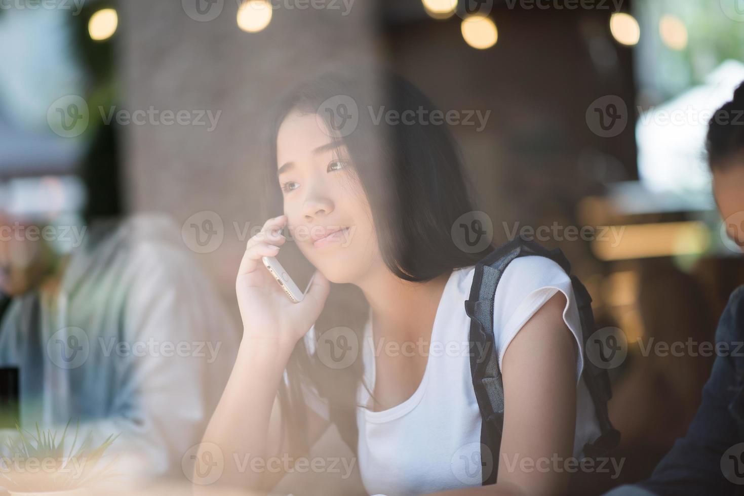 giovane donna utilizza lo smartphone nella finestra di un caffè foto