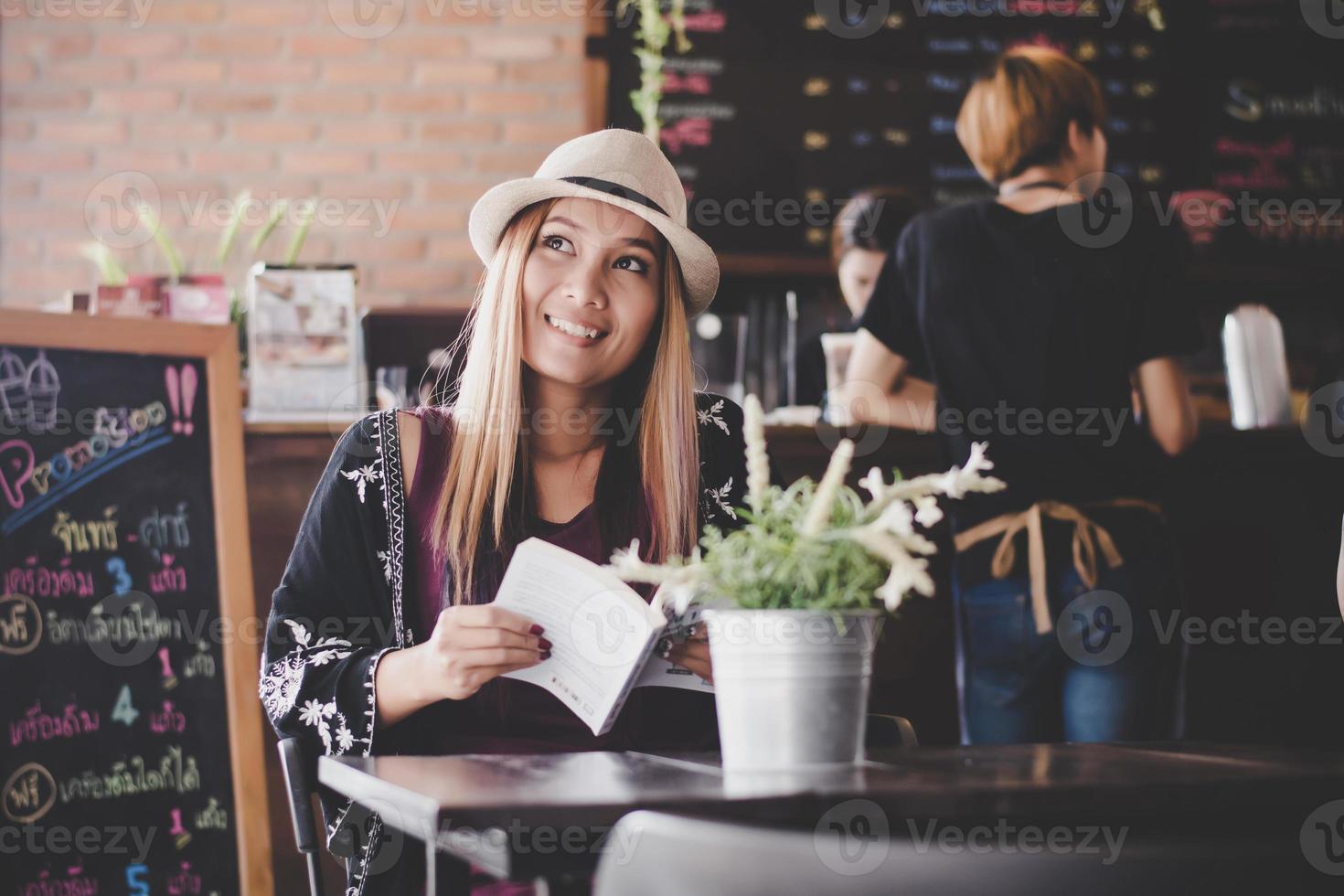 donna d'affari felice leggendo il libro mentre vi rilassate al caffè foto