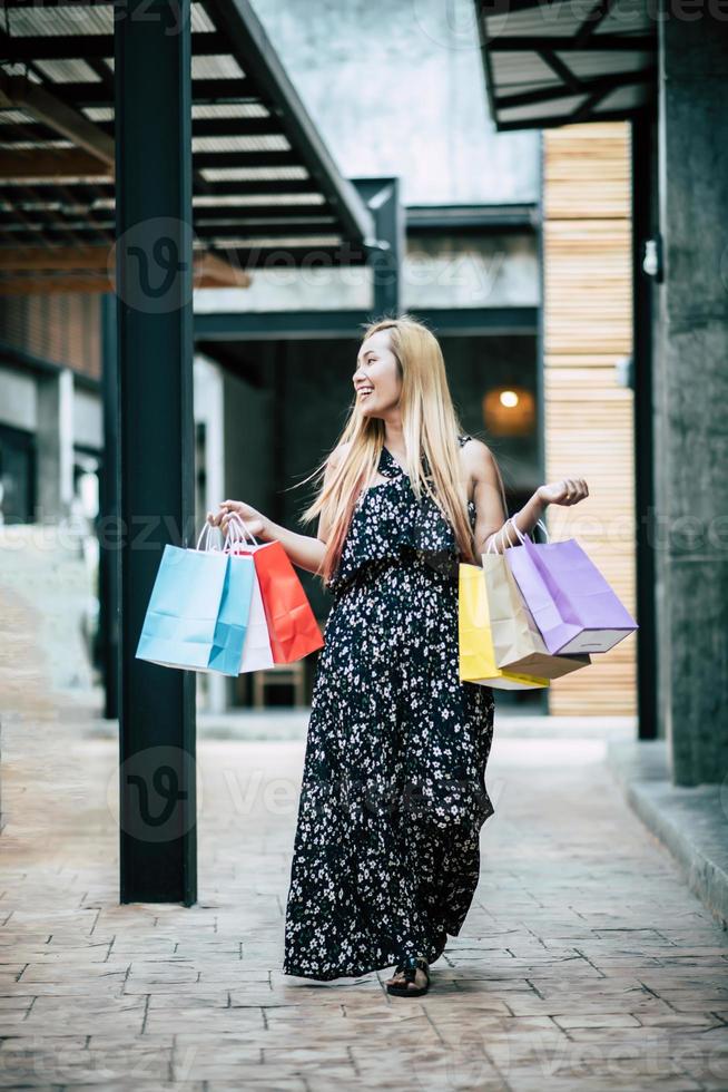 ritratto di una giovane donna felice con le borse della spesa a piedi per la strada foto