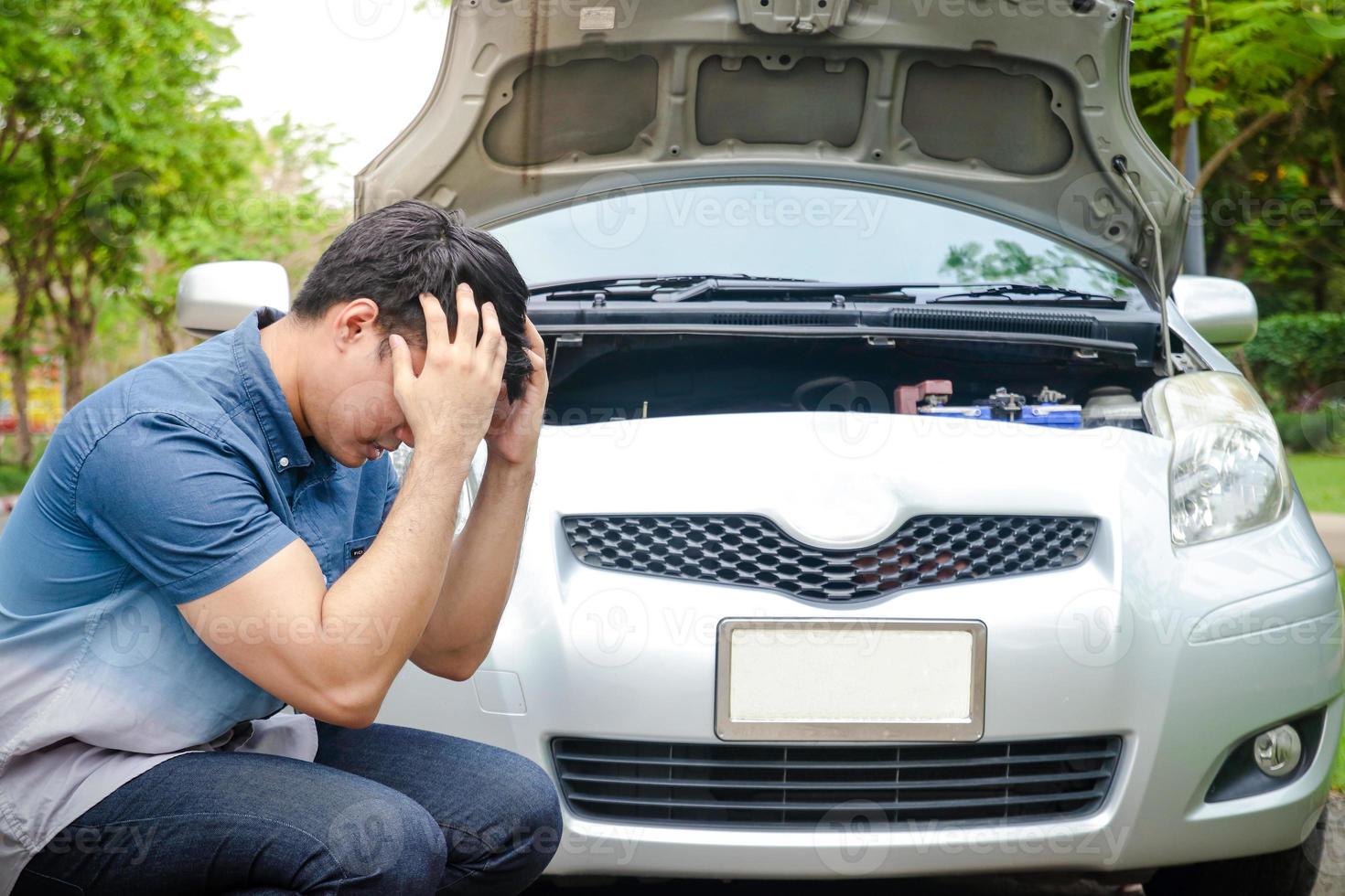 stressante asiatico uomini aumentare loro mani per hold loro teste il auto motore incidentato mentre in viaggio, parcheggiata su il ciglio della strada in attesa per aiuto. concetto di auto assicurazione foto