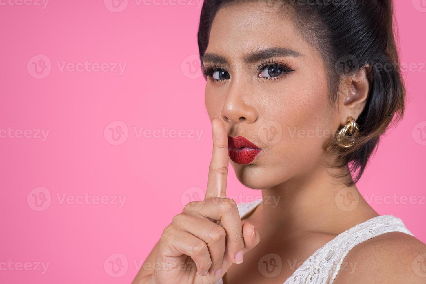 bella donna asiatica con labbra rosse che mostra il silenzio silenzio segno foto