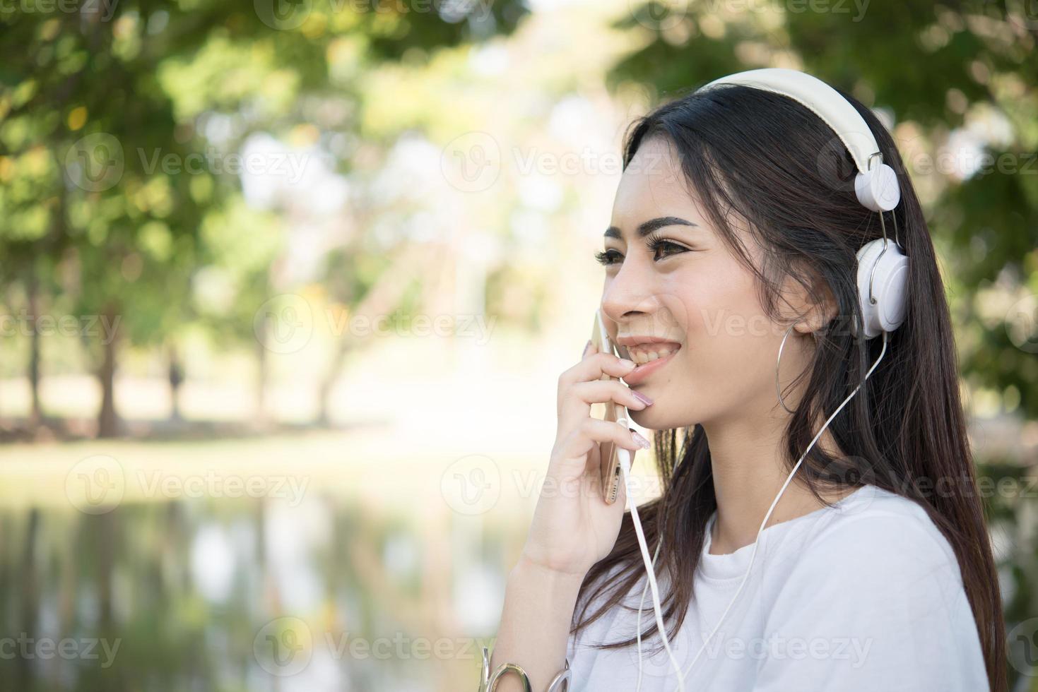 ritratto di una ragazza sorridente con le cuffie che ascolta la musica in natura foto