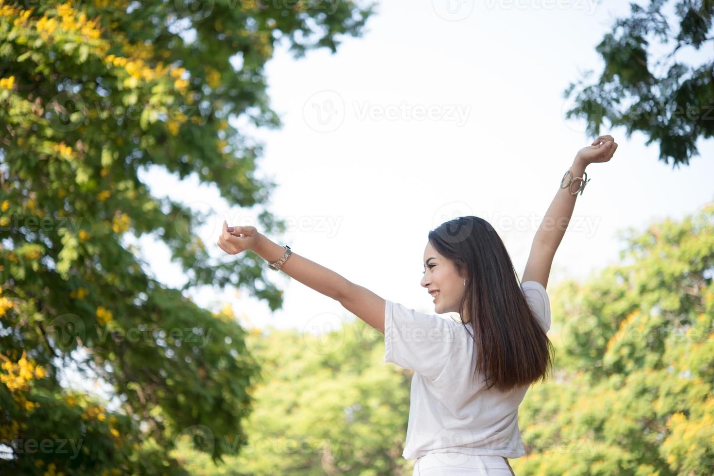 ritratto di una ragazza adolescente alzando le braccia e ridendo nel parco foto