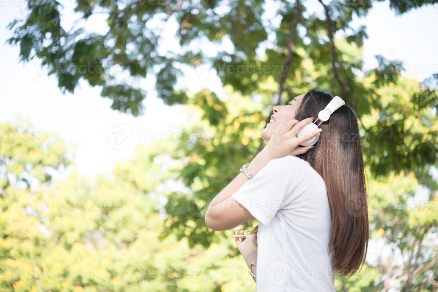 ritratto di una ragazza sorridente con le cuffie che ascolta la musica in natura foto