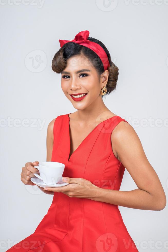 donna alla moda felice che tiene una tazza di caffè foto