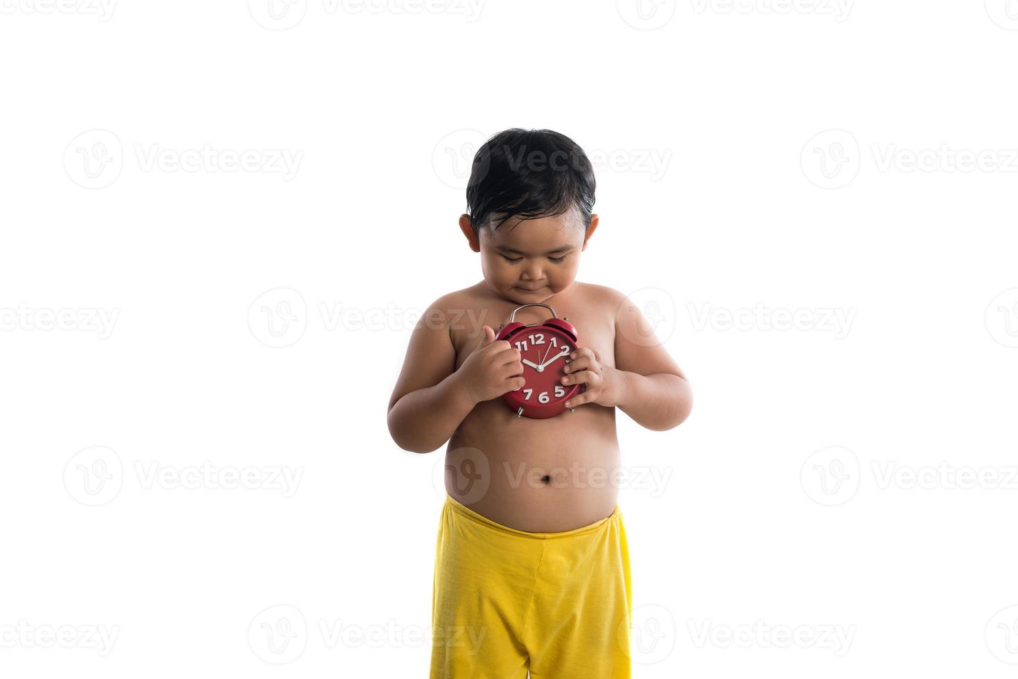 piccolo ragazzo asiatico in possesso di un grande orologio rosso, isolato su sfondo bianco foto