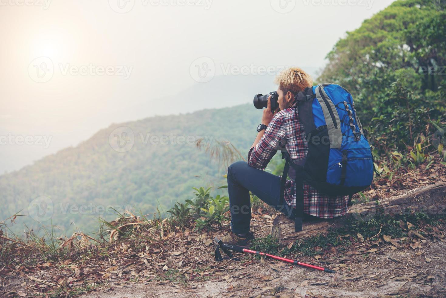 posteriore del giovane viaggiatore uomo con zaino in piedi sulla montagna e scattare una foto