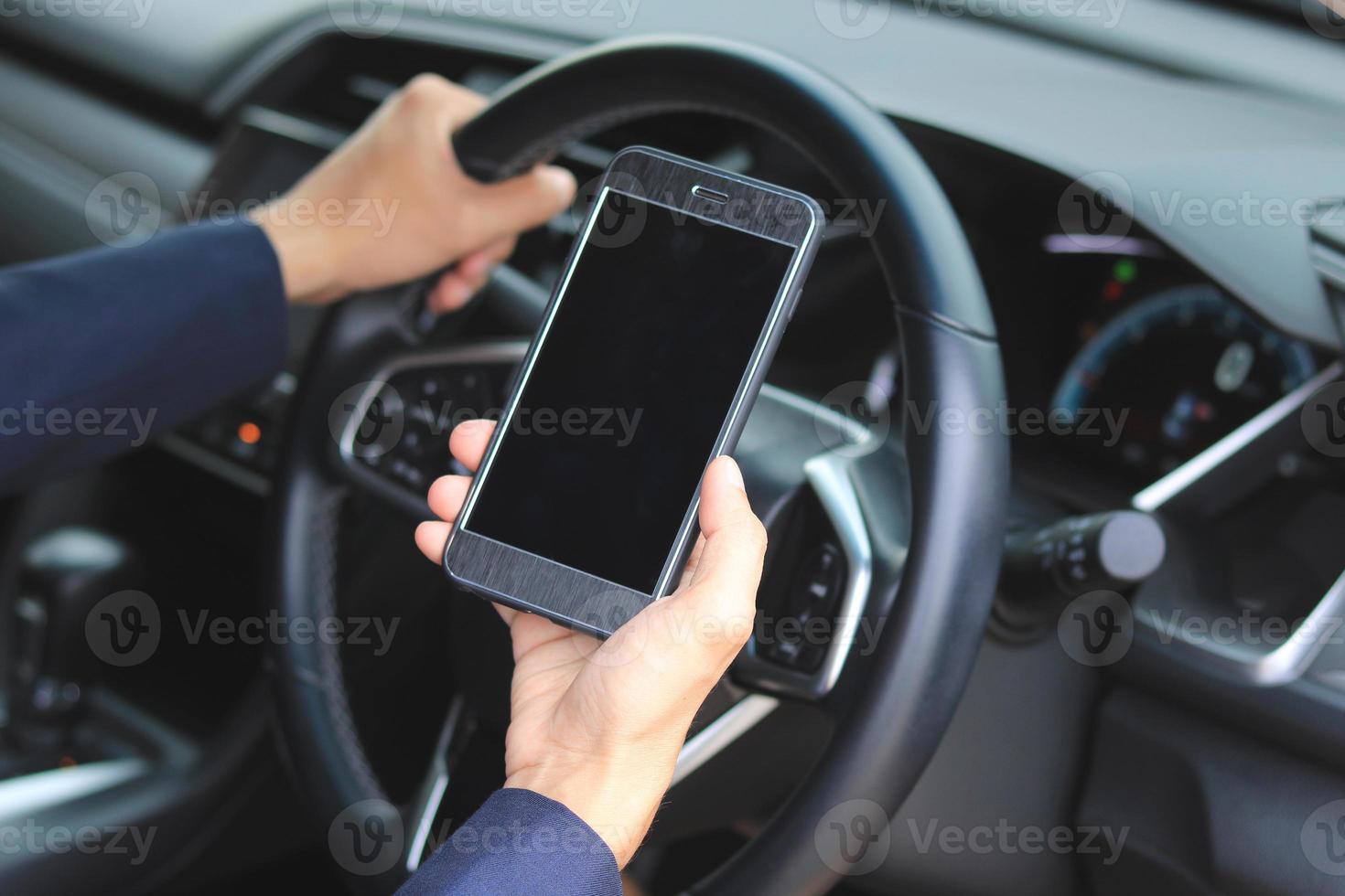 mani che tengono il telefono cellulare e il volante all'interno di un'auto foto