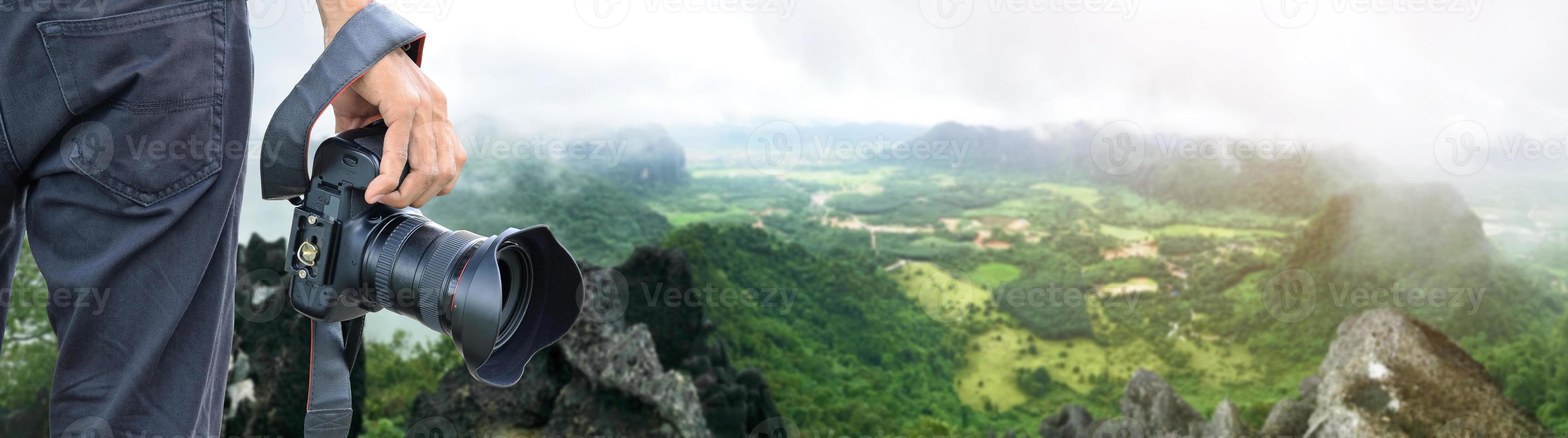 mano che tiene la fotocamera digitale che si affaccia sul panorama aereo del paesaggio verde foto