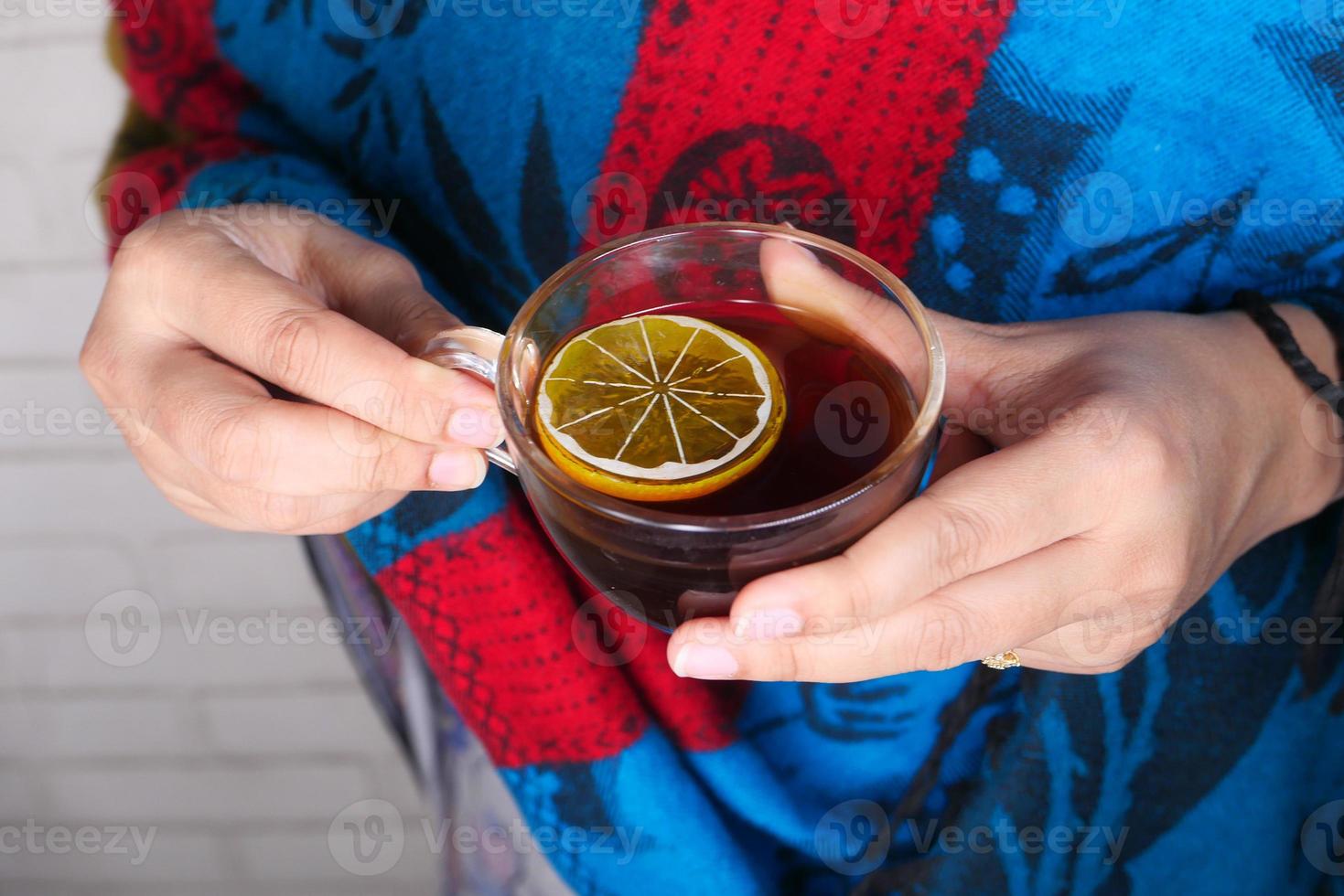 primo piano di una donna che beve il tè al limone foto