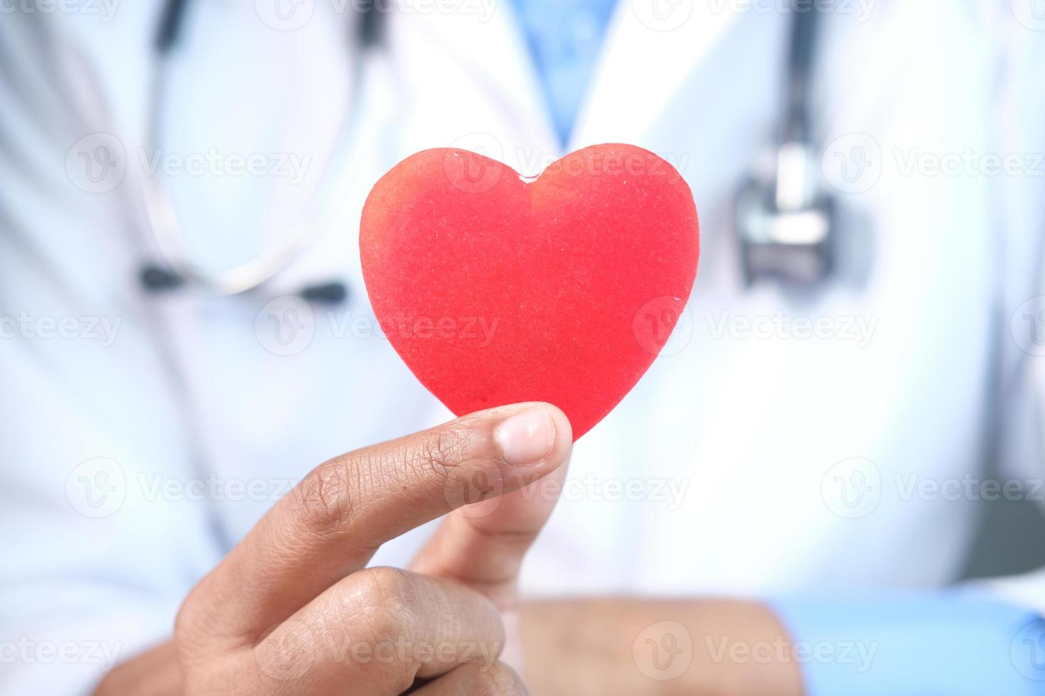 mano del medico che tiene un cuore rosso, primo piano foto