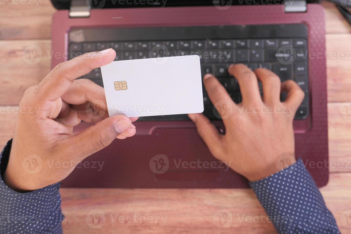 uomo in possesso di una carta di credito e utilizzando laptop per lo shopping online foto