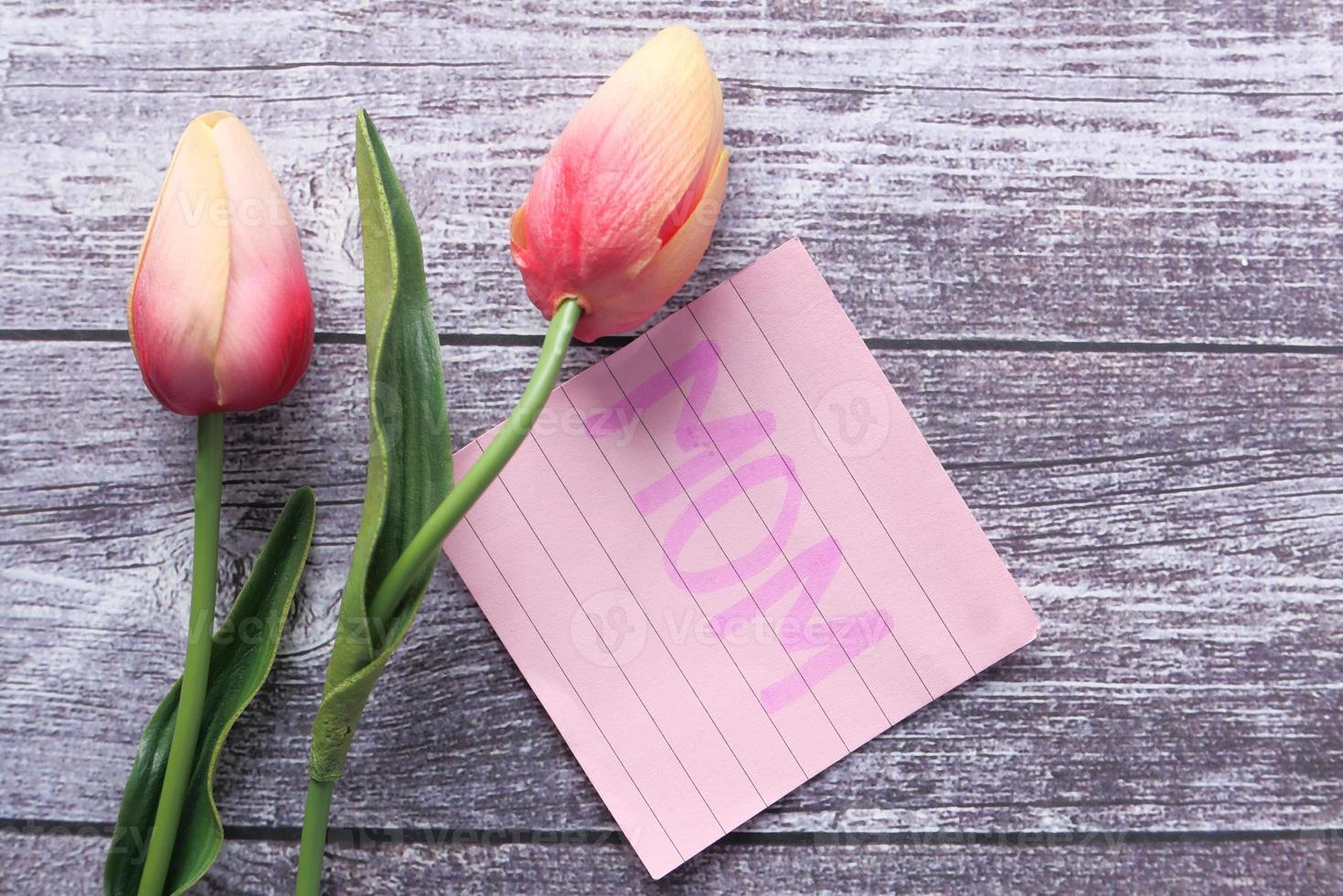 concetto di festa della mamma con fiori di tulipano e testo di mamma su una nota adesiva foto