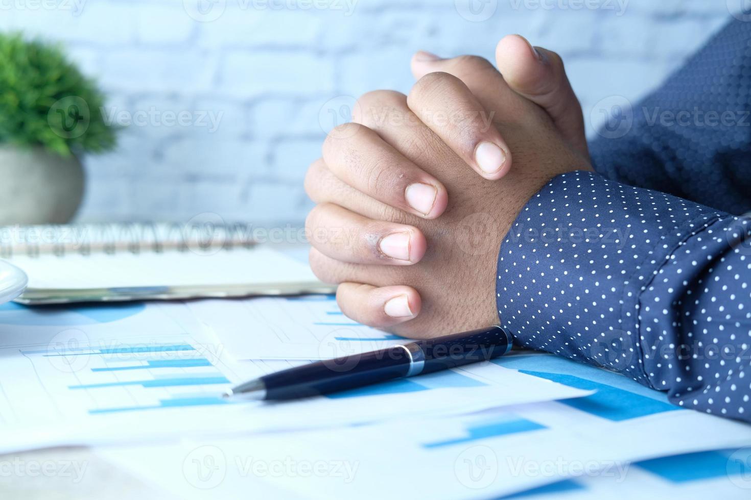 premuroso la mano dell'uomo con la penna su carta sulla scrivania in ufficio foto