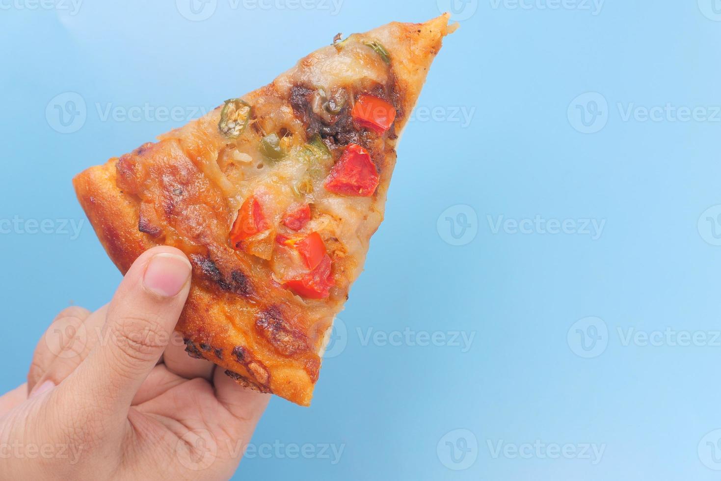 vista dall'alto della mano d'uomo raccogliendo una fetta di pizza su sfondo blu foto