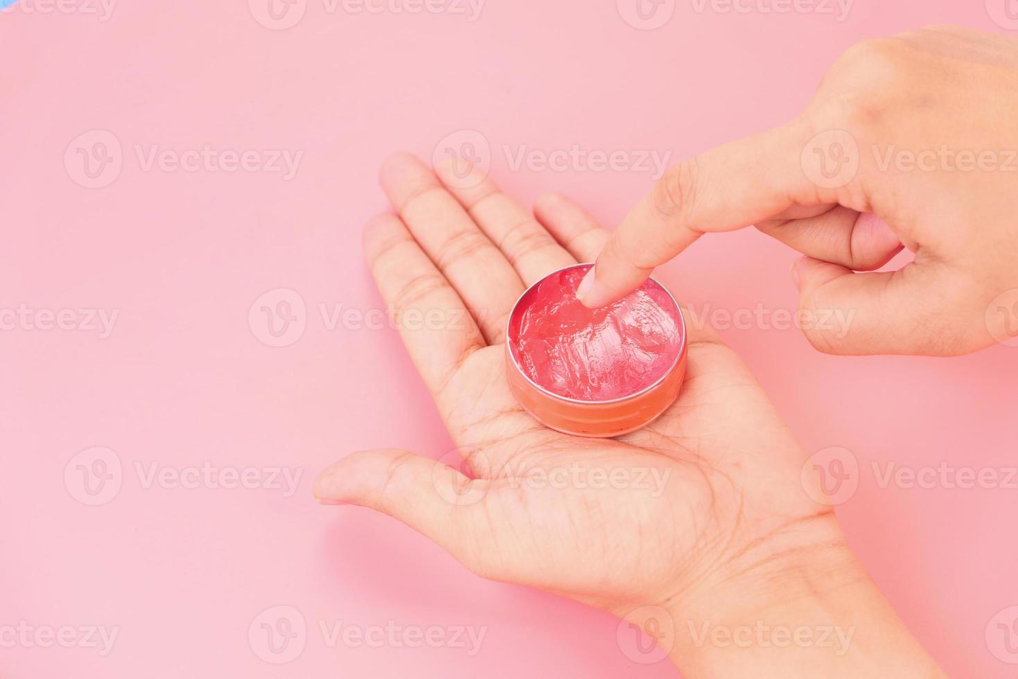 donna che utilizza gelatina di petrolio su sfondo rosa foto