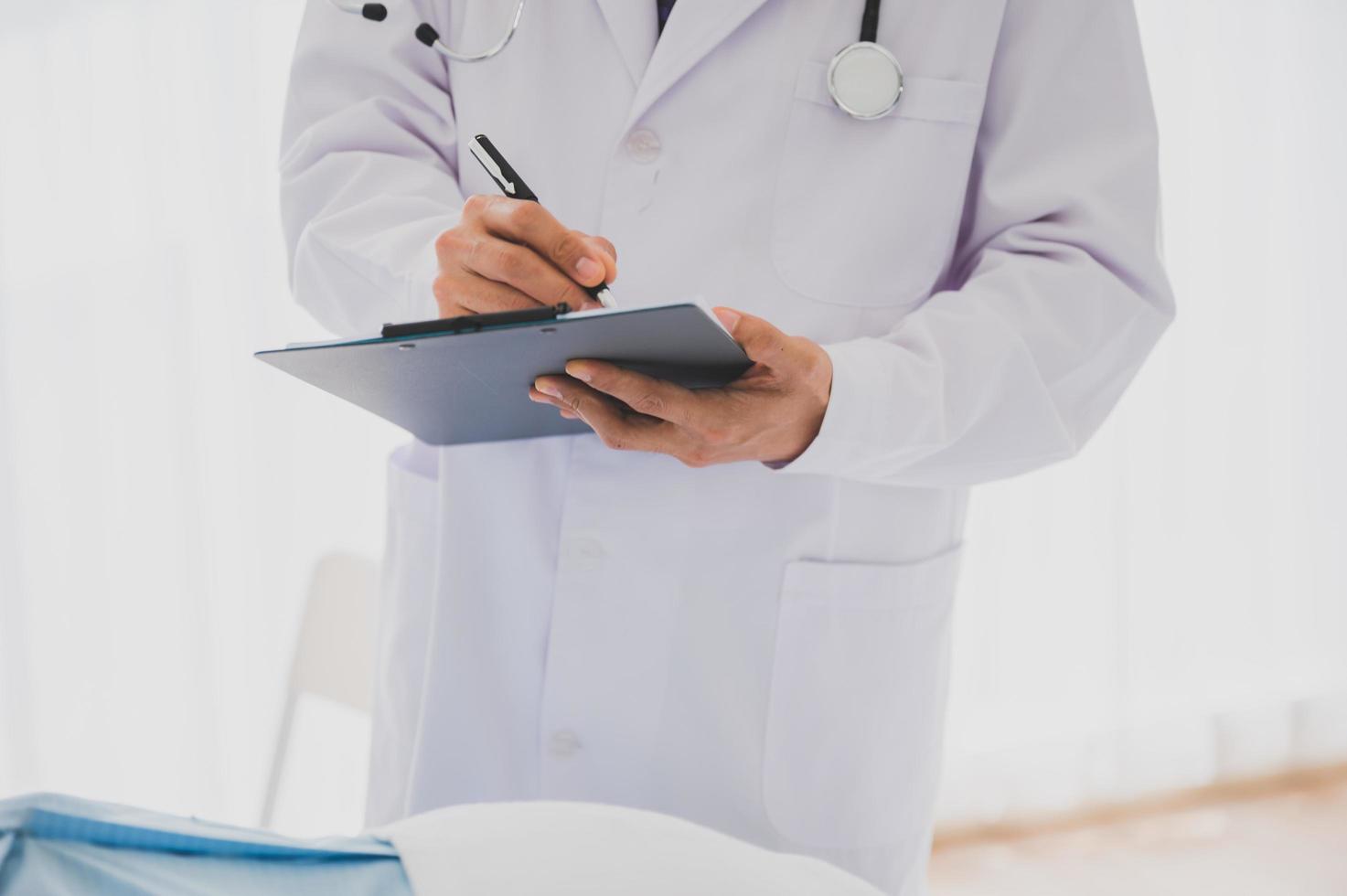 medico maschio con camice da laboratorio e stetoscopio tenendo appunti e penna foto