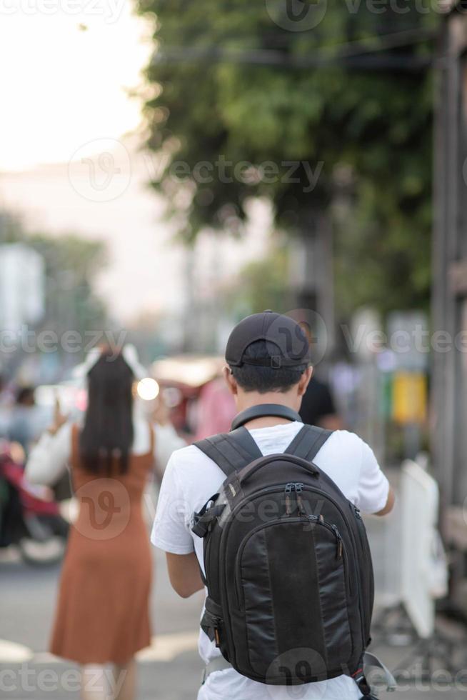 il indietro di il giovane fotografo è trasporto un' zaino dietro a il suo indietro come un' telecamera Borsa per preparare per registrazione il eventi quello Maggio si verificano durante il suo viaggi perché lui è un' fotografo. foto