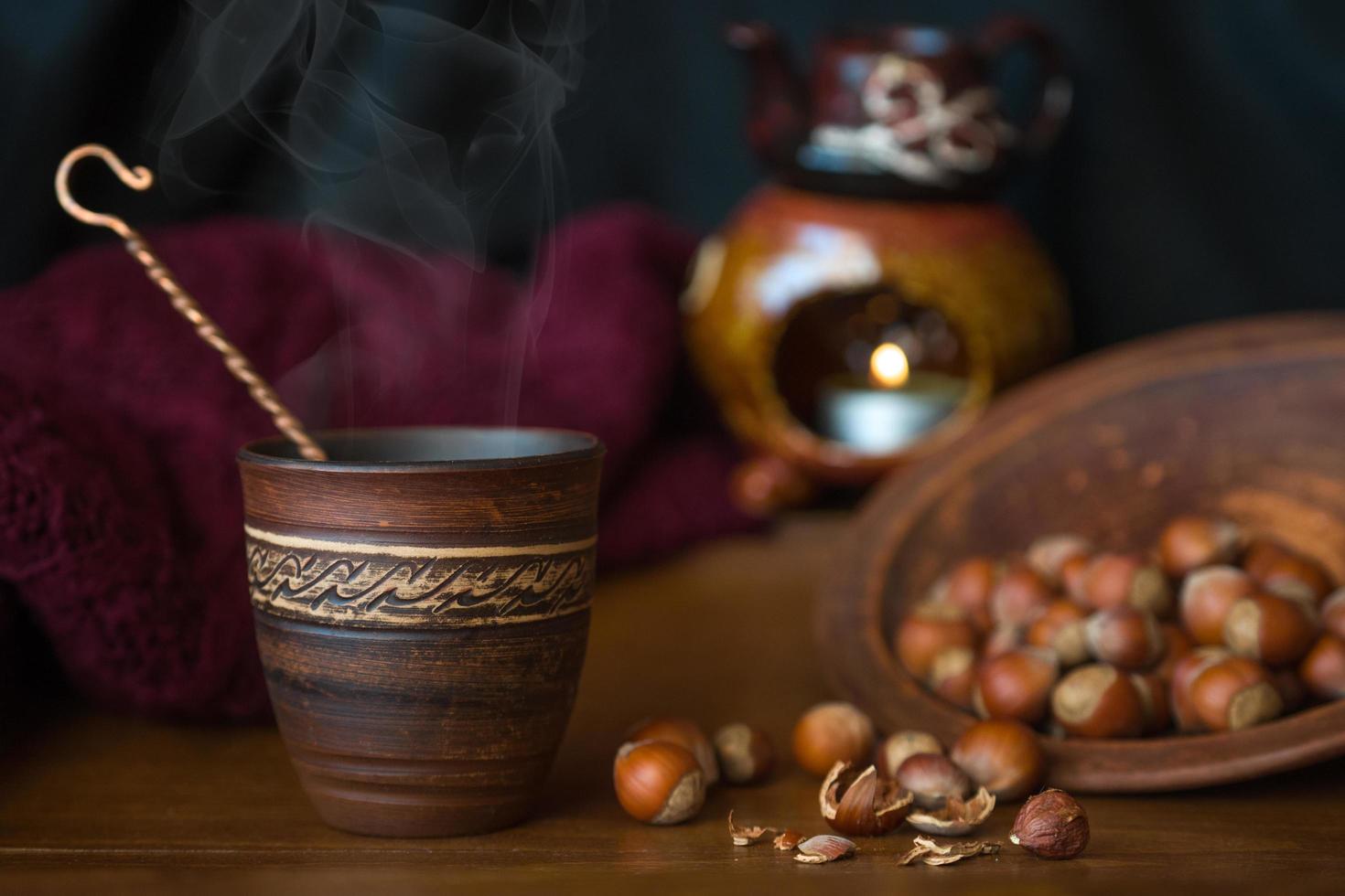 tazza di ceramica decorata accanto alle nocciole sul tavolo foto