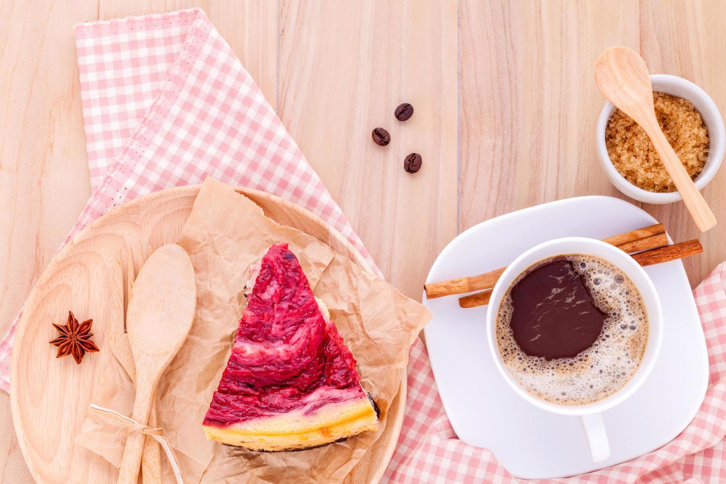 torta di lamponi con una tazza di caffè su fondo in legno foto