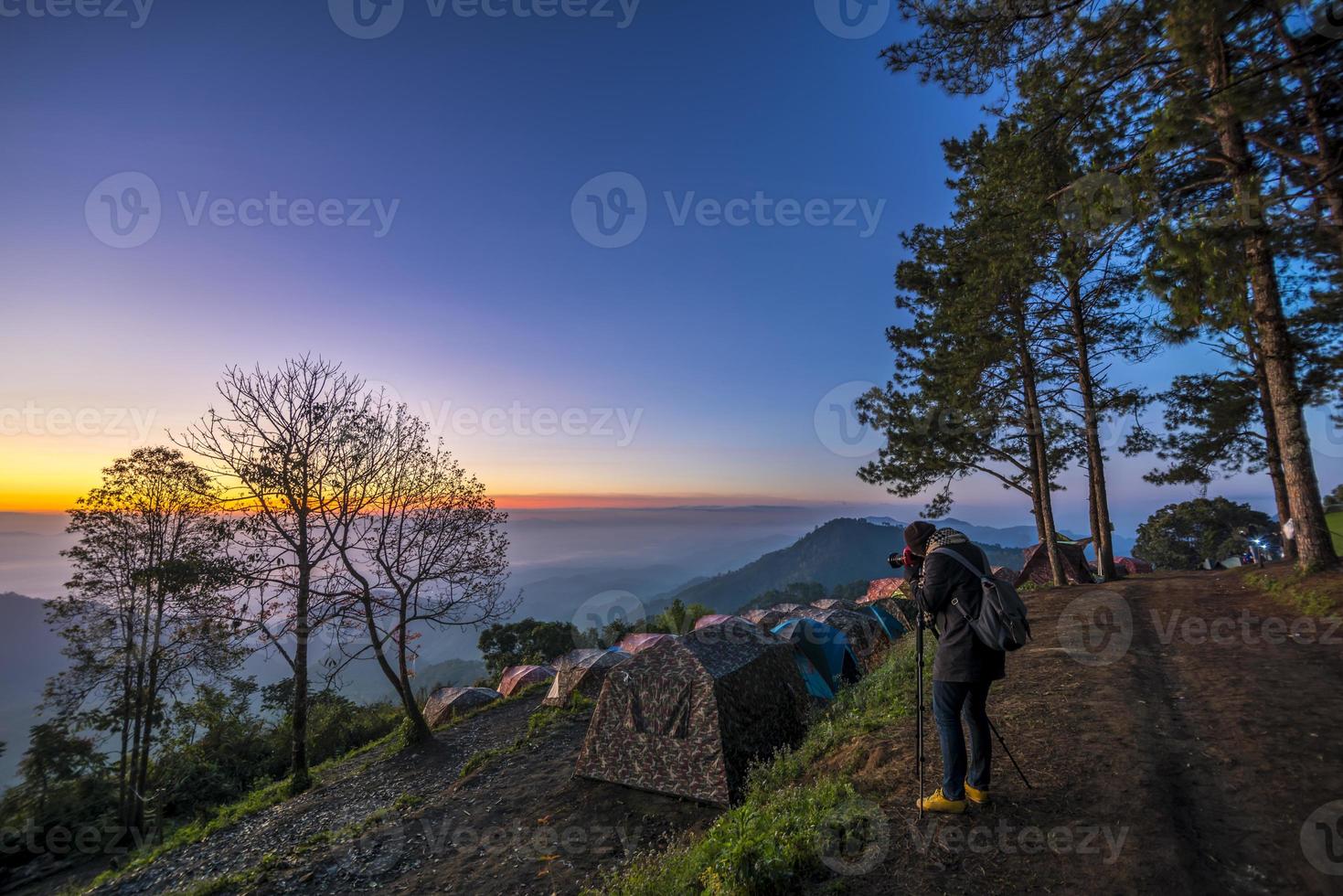 persona che fotografa sulla cima di una montagna foto