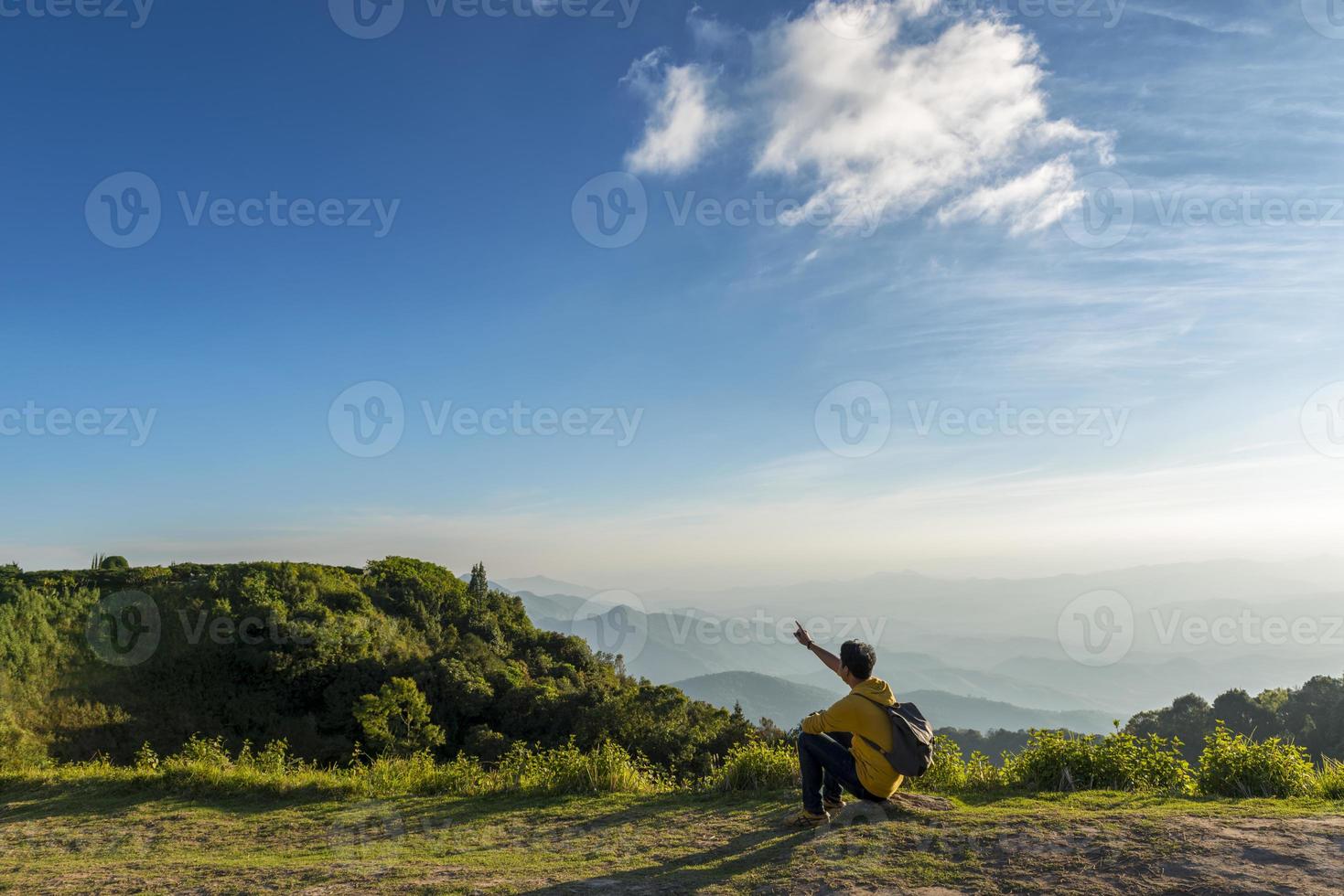 uomo viaggiatore seduto sulla roccia con sfondo di montagne foto