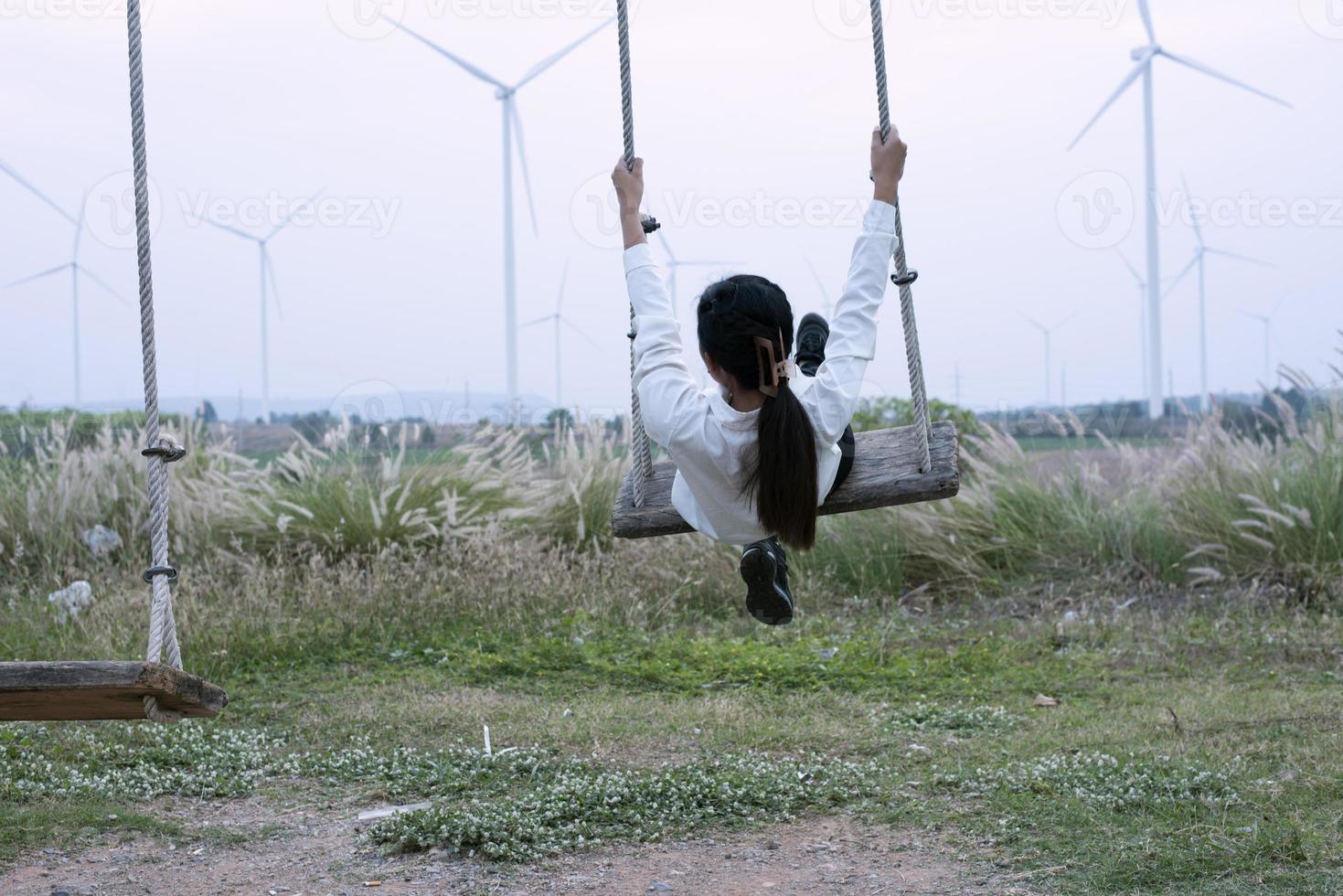 bellissimo giovane madre figlia si siede e rilassare a estate prato sfondo e mulini a vento, mulini a vento come alternativa energia fonti, sostenibile risorsa concetto, Comunità persone con mulini a vento foto
