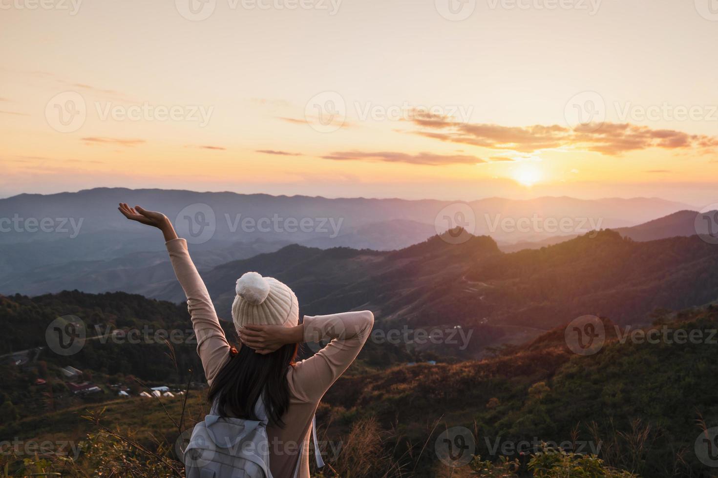 viaggiatore felice della giovane donna che si rilassa e che guarda il bel tramonto sulla cima della montagna foto