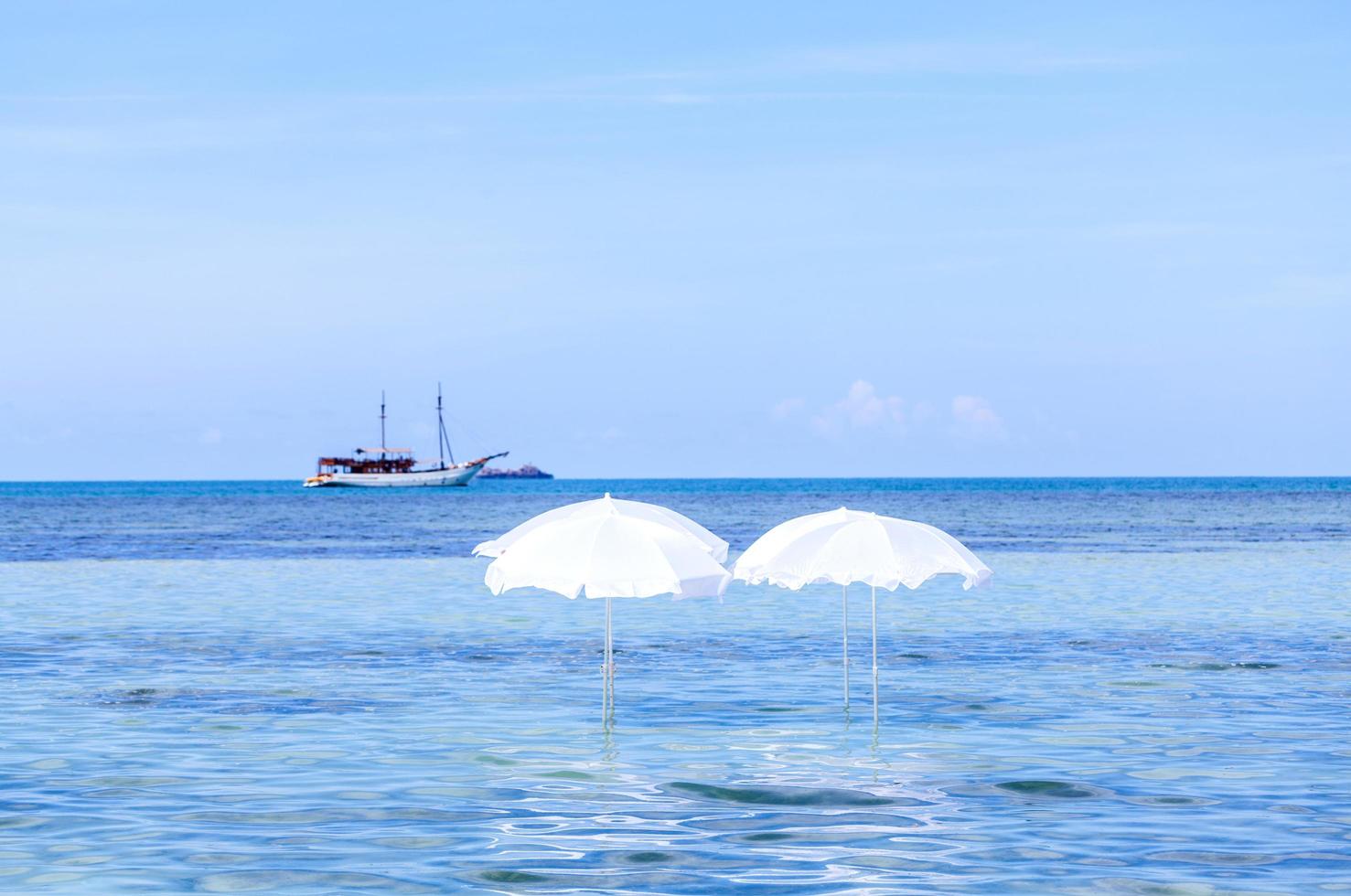 ombrellone bianco sulla spiaggia tropicale estiva con barca foto