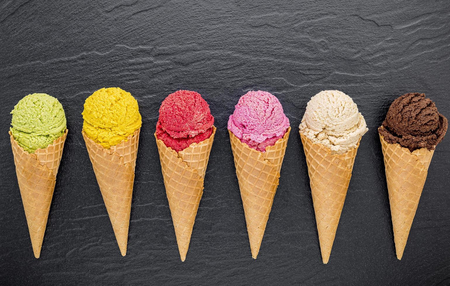 gelato colorato in coni su sfondo scuro foto