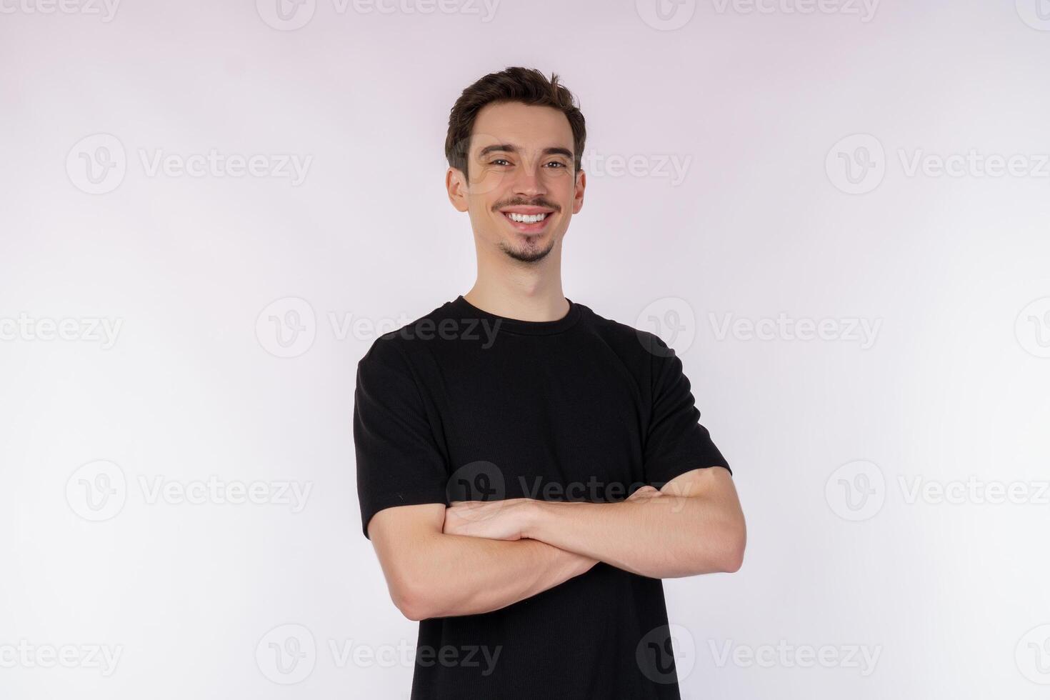 ritratto di giovane bello uomo indossare nero maglietta, in piedi con attraversato braccia con isolato su studio bianca sfondo foto