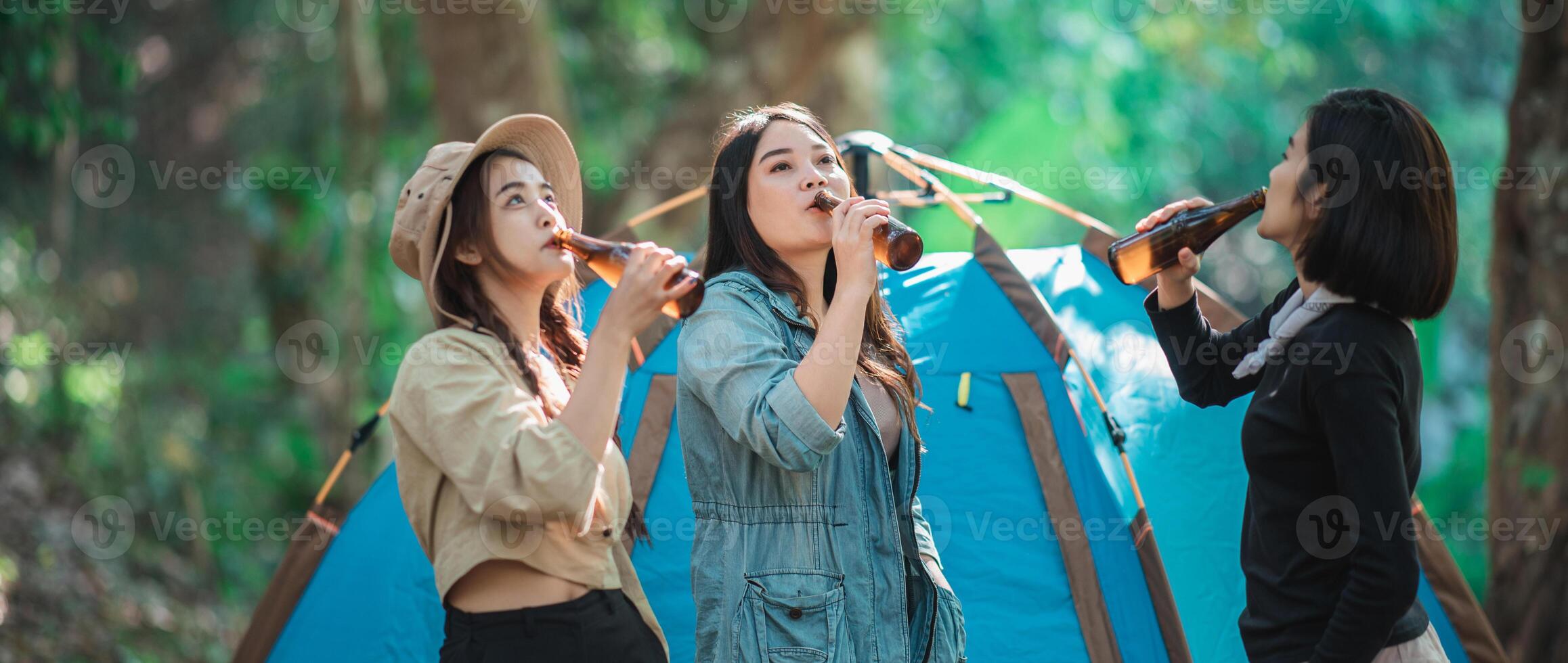 giovane donne rallegrare e bevanda bevanda davanti di campeggio tenda foto